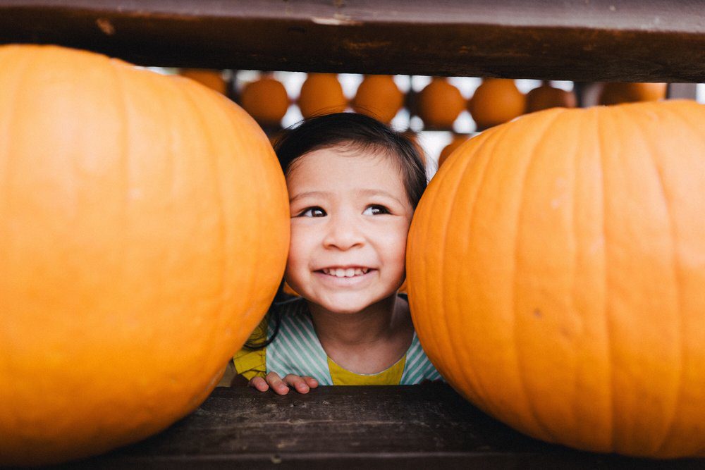 Child sitting with pumpkins.