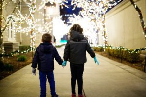 Two children walking near holiday lights