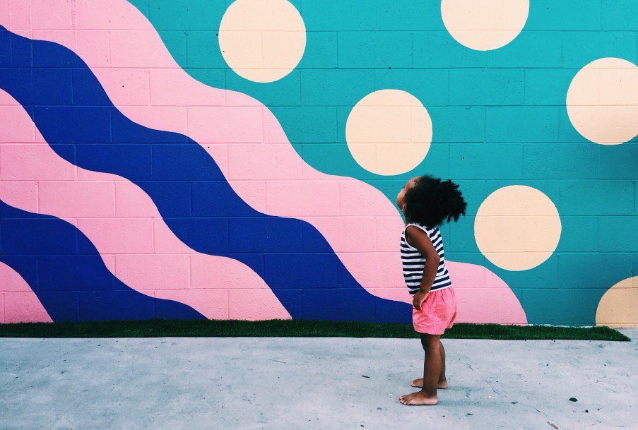 Child standing in front of a colorful wall