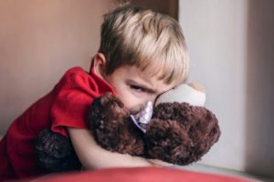 Upset child hugging a teddy bear.