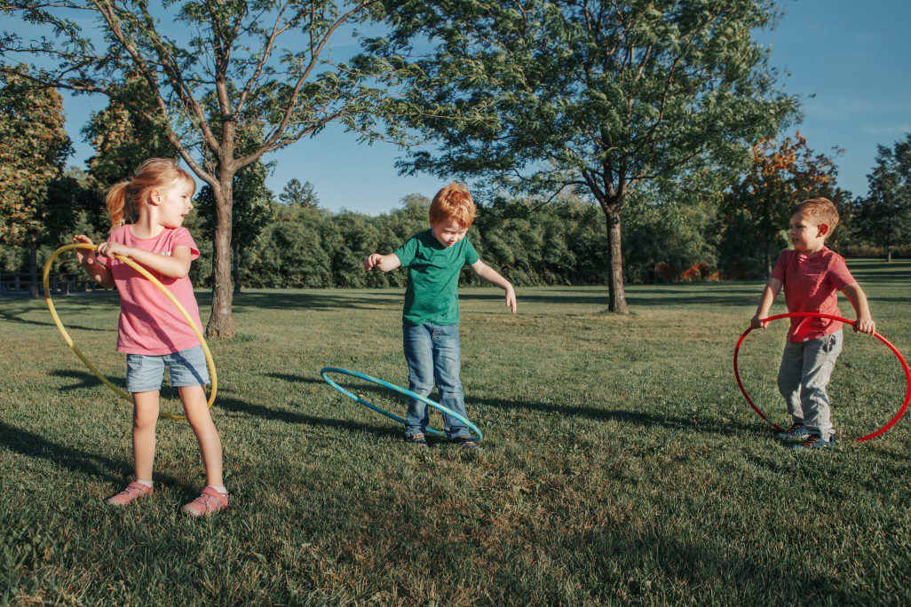 Children hula hooping in a park.