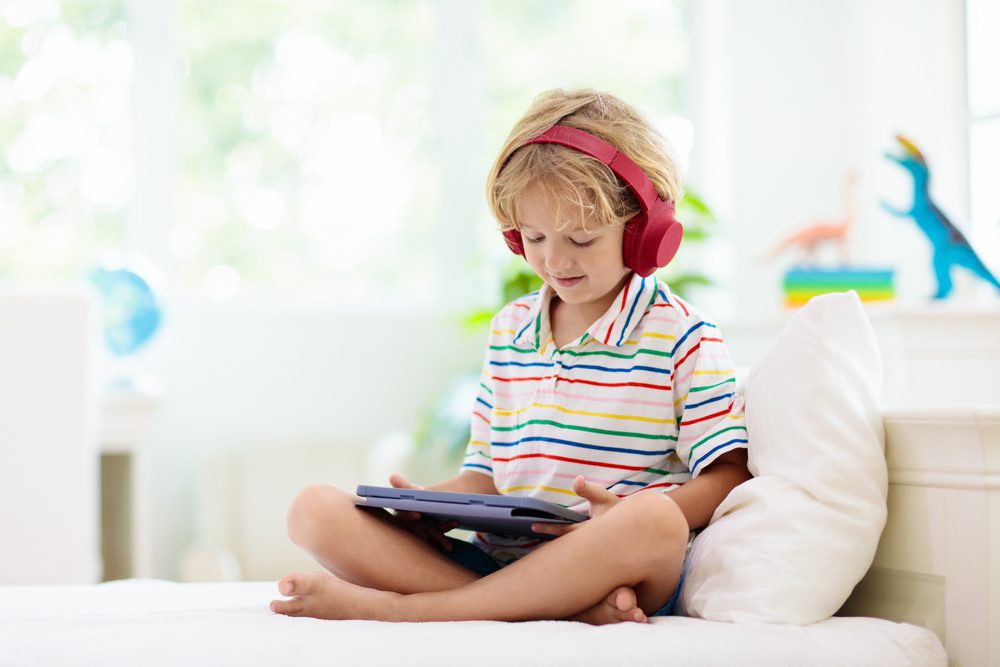 Child wearing headphones and looking at a tablet 