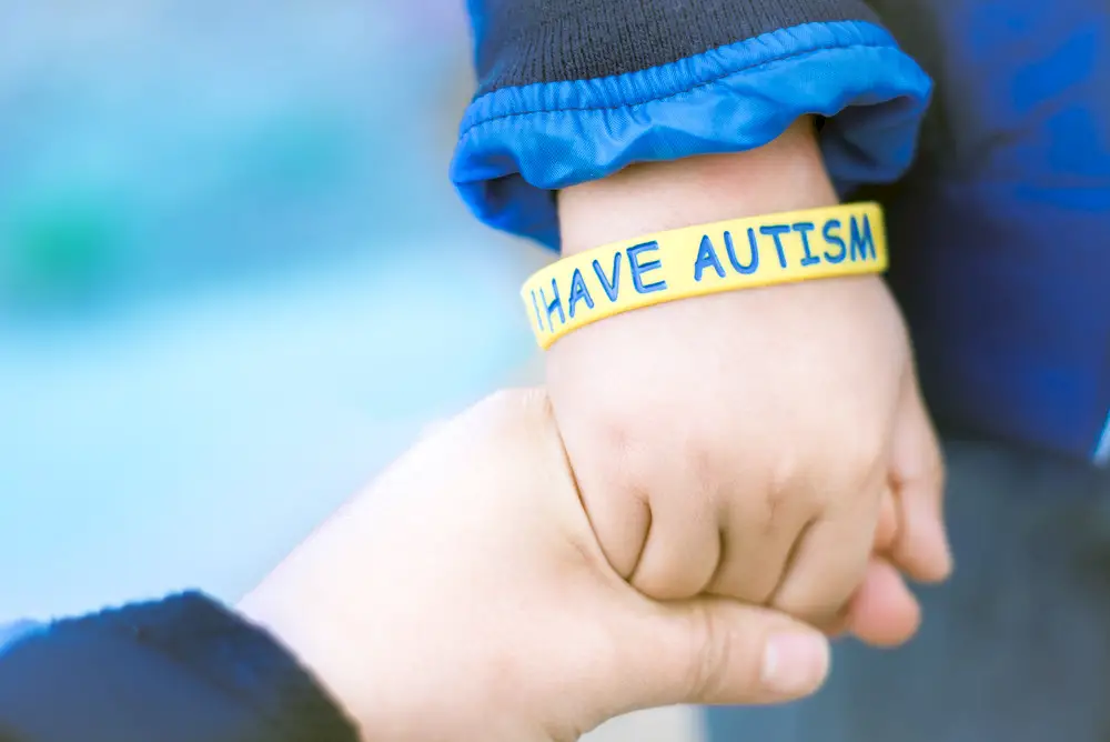 A child wears a bracelet that says I Have Autism