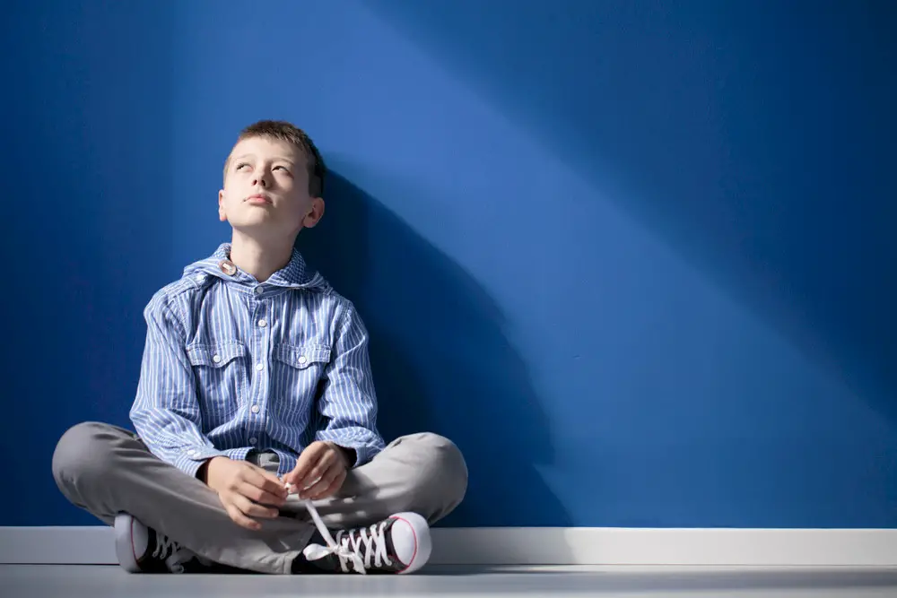 A child sits by a blue wall